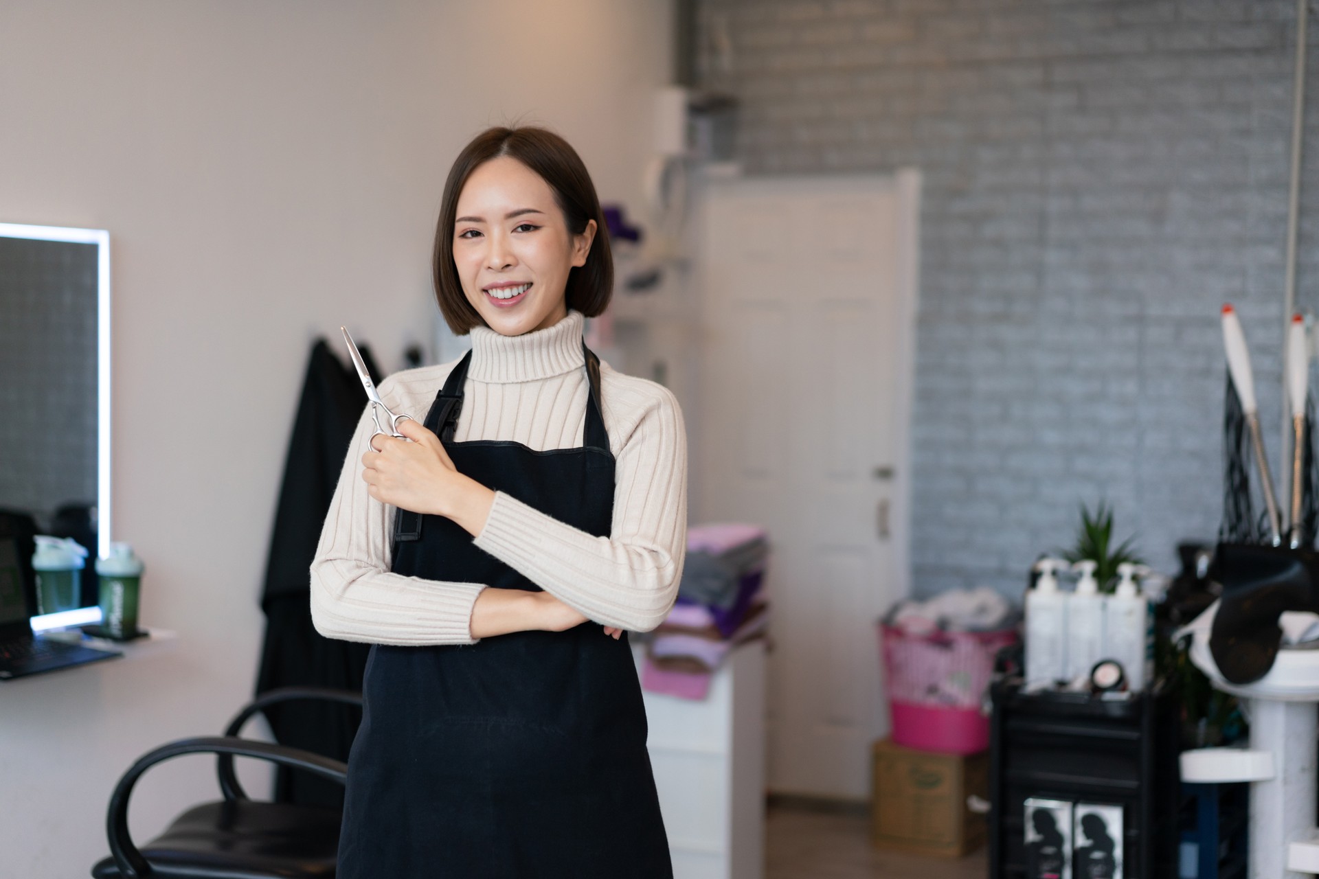 Portrait of a young asian female hairdresser holding qualified haircut tools.